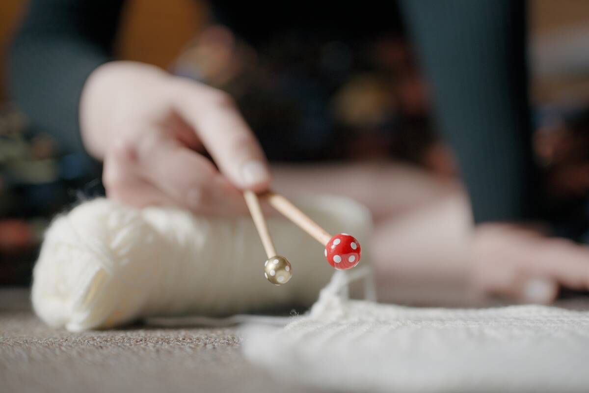 young woman holding crochet hook above yarn